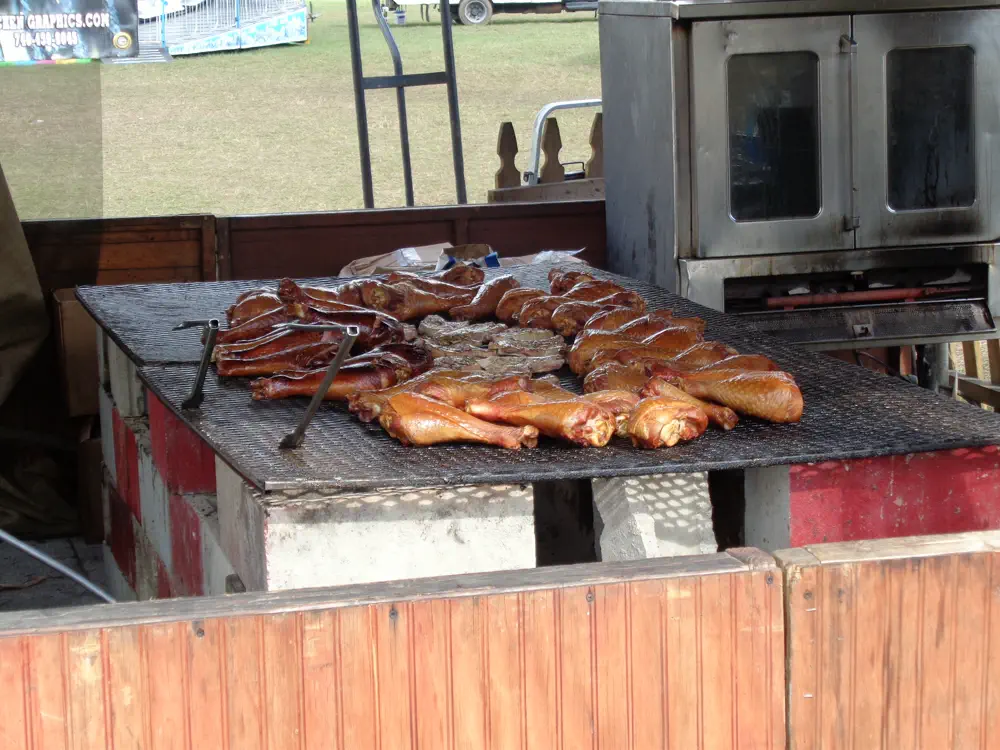 Smoked turkey legs laid out across a fairground grill